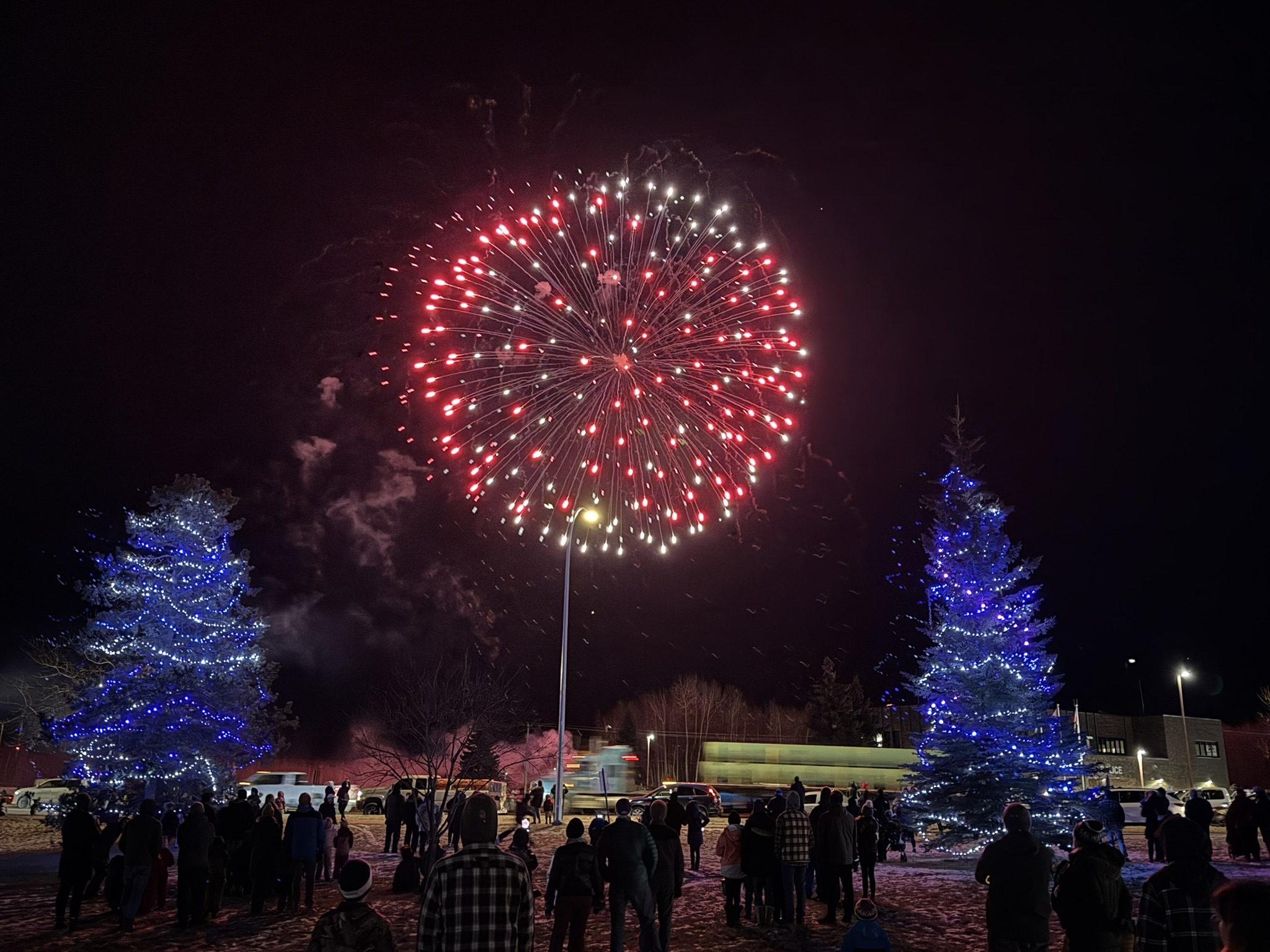 Firework over lit Christmas trees